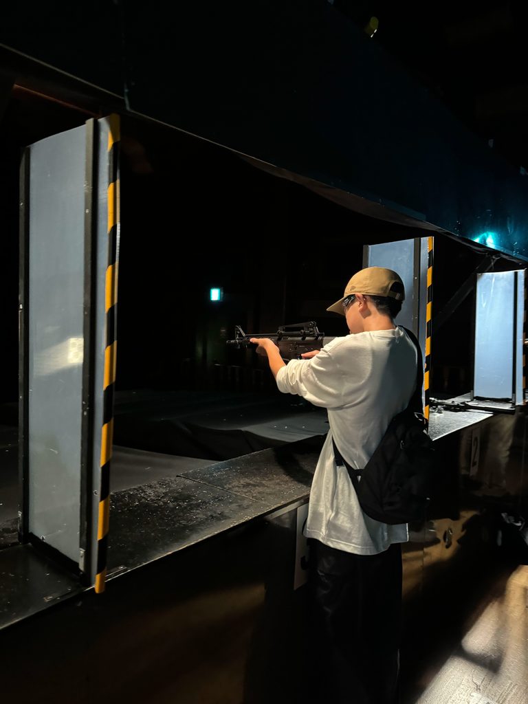 Trying the shooting game attraction inside a dark arcade at Huis Ten Bosch