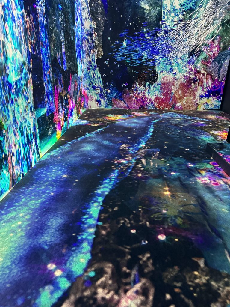 Projection-mapped floor glowing blue and pink inside the digital art attraction