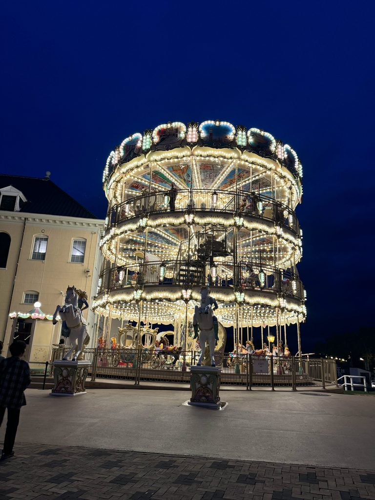 Illuminated two-tier carousel glowing at night in Huis Ten Bosch