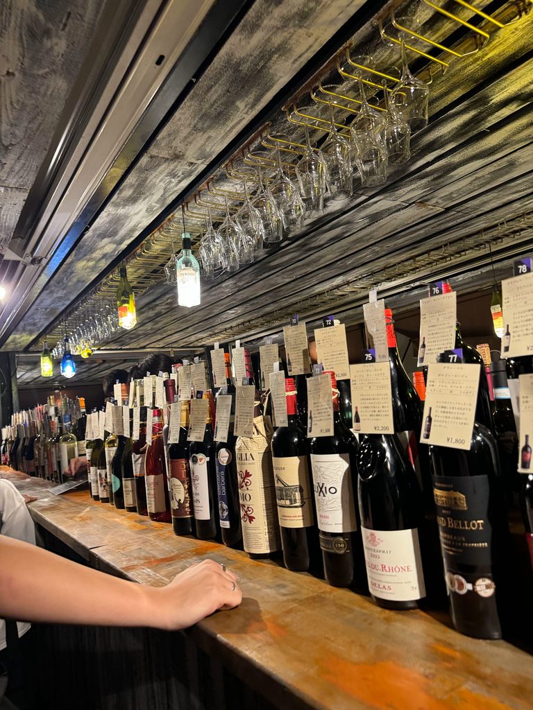 Row of wine bottles with handwritten tasting notes above the bar counter