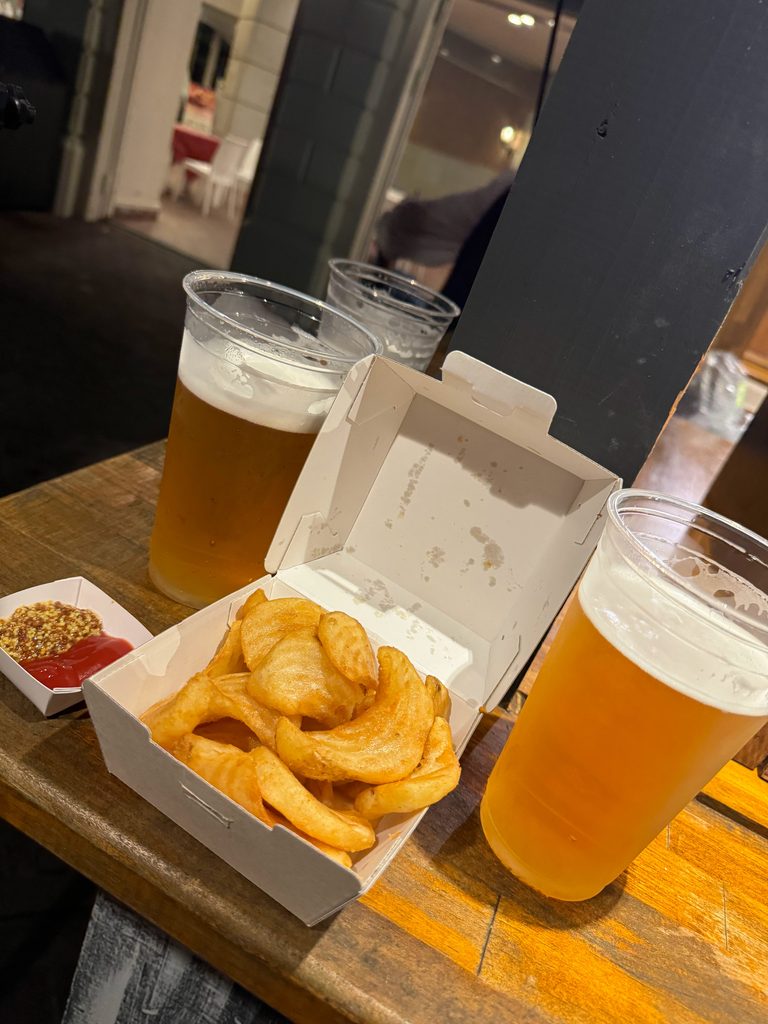 Two glasses of beer and a box of onion rings on the bar counter