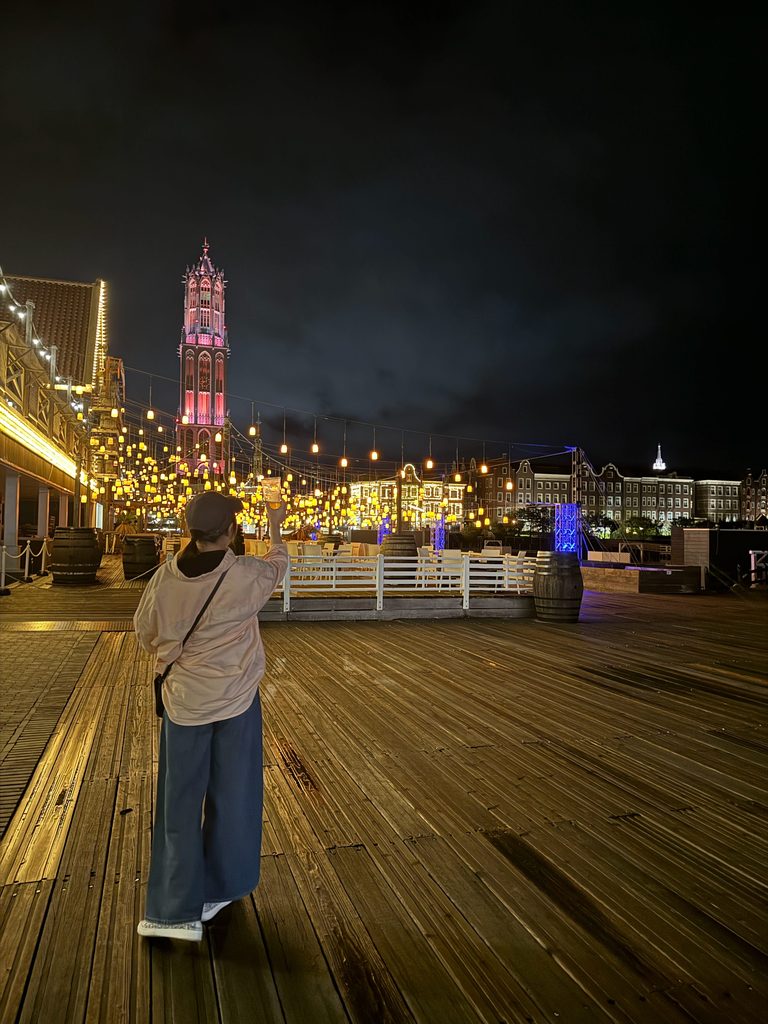 Walking the night boardwalk with the red-lit Domtoren and string lights ahead