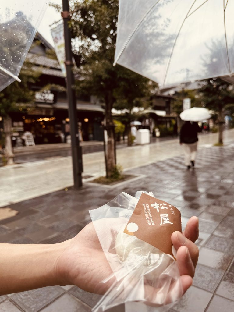 Holding a freshly wrapped umegae-mochi on the rainy Dazaifu shopping street