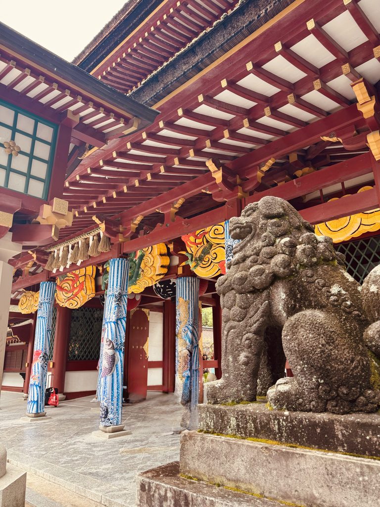 A stone komainu guardian beside the vermilion gate of Dazaifu Tenmangu