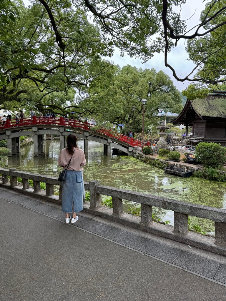 Crossing the arched red bridge over the pond at Dazaifu Tenmangu