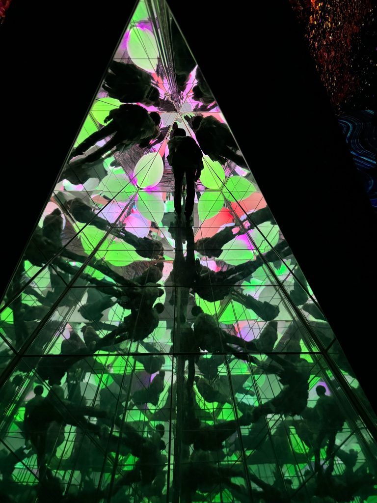 A glowing green and pink prism artwork inside teamLab in Fukuoka