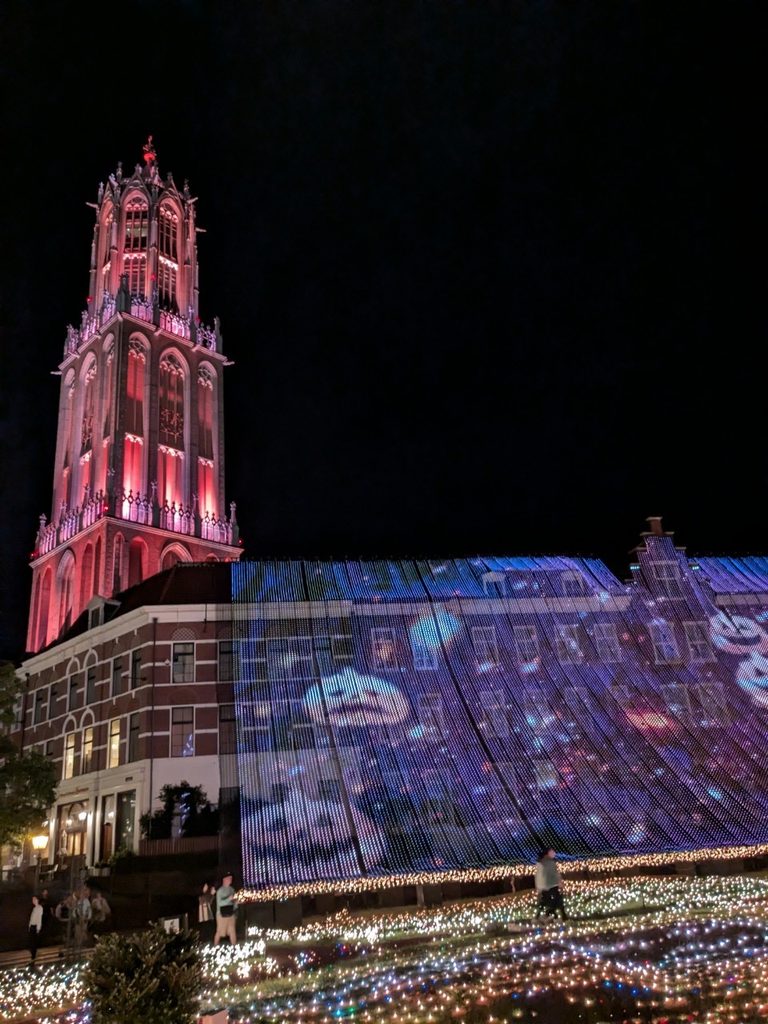The red-lit Domtoren rising above a hillside of projection-mapped light at the Huis Ten Bosch illumination
