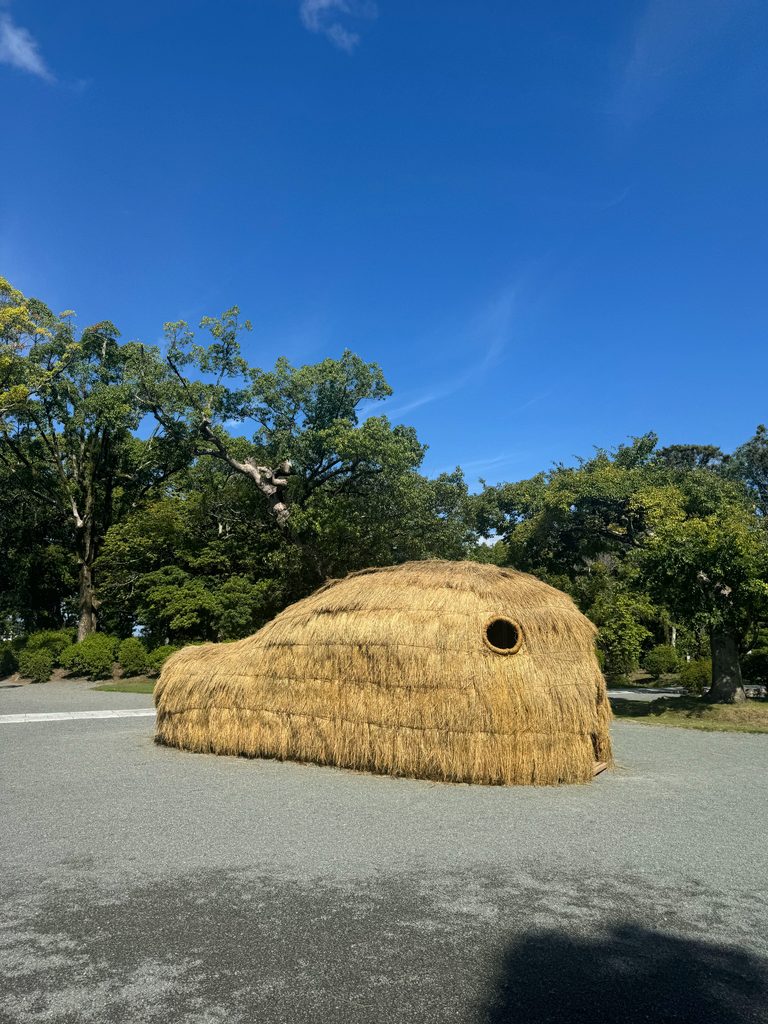 A large straw sculpture on the grounds at Munakata Taisha under a blue sky