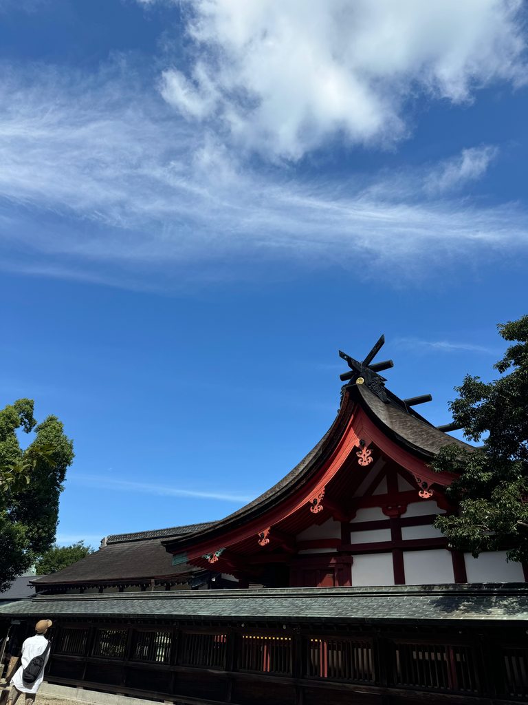 The vermilion roof of Munakata Taisha against a clear blue sky