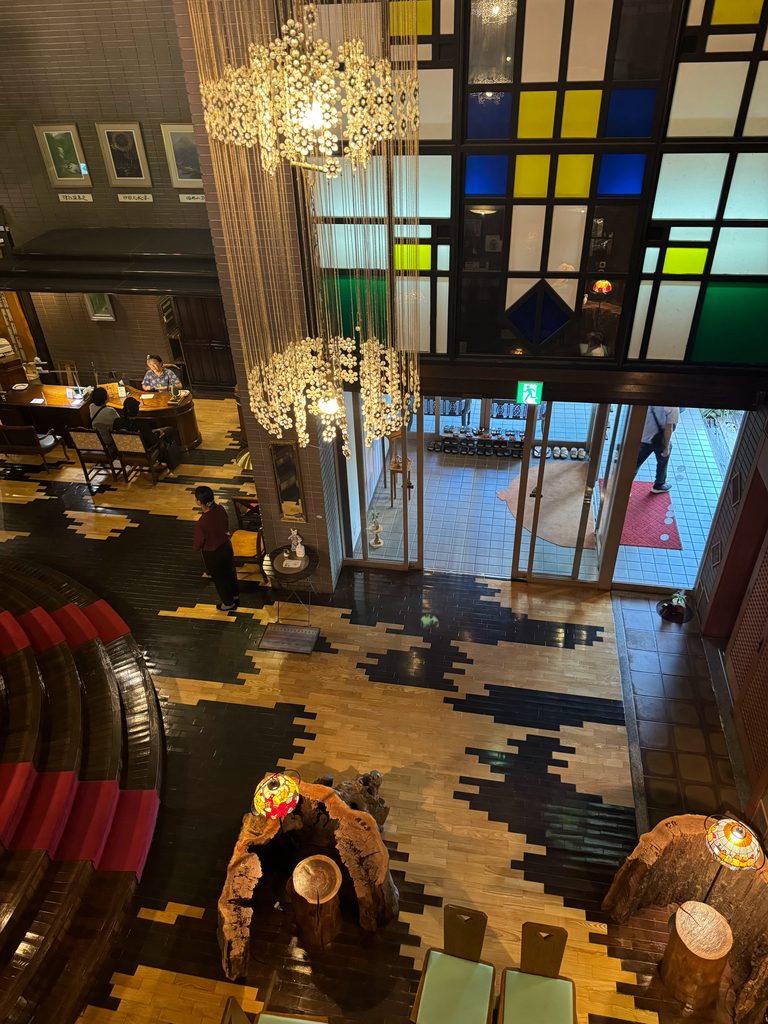 View of the ryokan lobby from above, with chandeliers and a colorful stained glass window