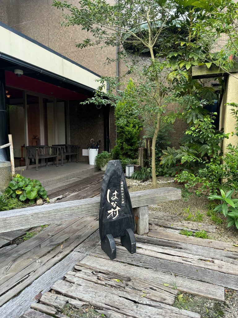 The entrance of Kahori no Sato Hanamura, a ryokan in Yufuin, with its stone name sign
