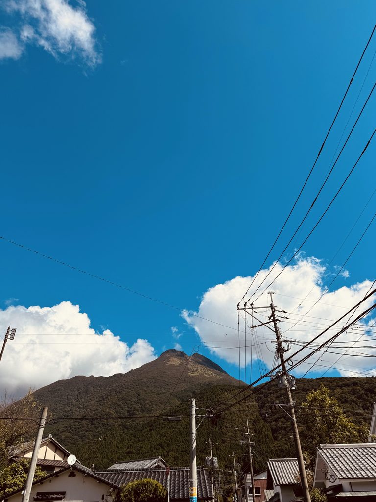 Mt. Yufu rising above the rooftops of Yufuin under a clear blue sky