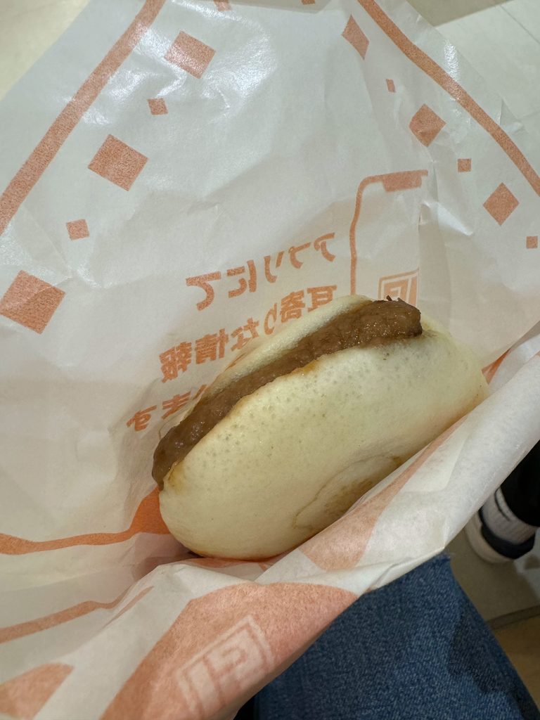 A soft steamed bun with a savory filling, a street food snack from Yufuin